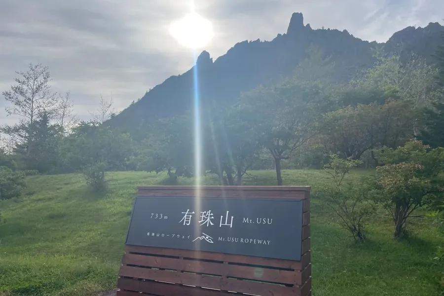 有珠山の案内板と、山の上から差しこむ日の光。